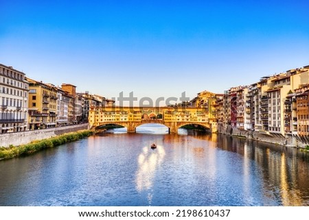 Golden Sunset over Ponte Vecchio Bridge with Traditional Boat on the Arno River, Florence, Italy 