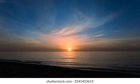 A golden sunset reflects off calm waters, with a sky painted in soft clouds and warm hues.   - Powered by Shutterstock