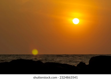 Golden Sunset Scene in Sri lanka. Little hazy , sea waves. and beach rocks can be seen. sky orange yellow color minor lens flare