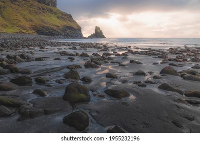 Golden sunset or sunrise light on seascape and sea stack along the rocky shore at low tide at Talisker Bay Beach on the Isle of Skye, Scotland