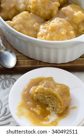 Golden Syrup Dumplings On Table With One Portion On Plate With Bite Taken Vertical