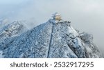 A golden temple crowns a snow-covered peak, surrounded by misty clouds, with terraced steps ascending the frosty path.