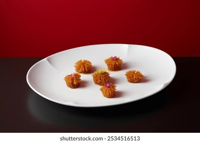 Golden, textured food bites on a wide white plate, garnished with vibrant pink and yellow edible flowers against a bold red background. - Powered by Shutterstock