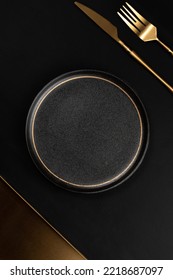Golden Tray, golden tablewares and vacant black ceramic dinner plate are placed on a the background is black leather. Luxurious, sumptuous fine tableware.Flat lay, top view, banner,horizontal photo - Shutterstock ID 2218687097