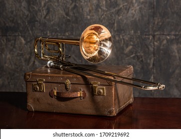 Golden trombone musical instrument lies on an old suitcase