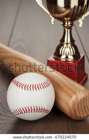 golden trophy cup and baseball bat and ball on the wooden table
