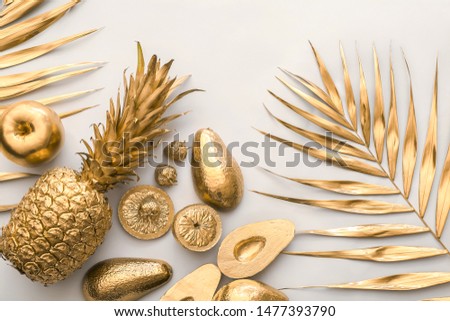 Golden tropical leaves and fruits on light background