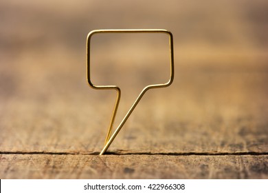 Golden tweet or remark. Blank speech bubble made of gold wire on rustic or grunge wood ready for inserting text. Shallow depth of field. - Shutterstock ID 422966308