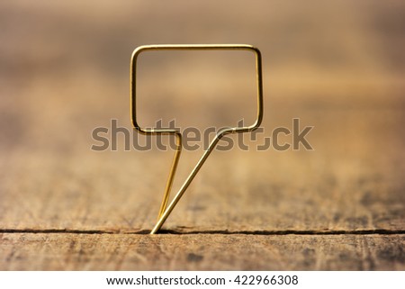 Golden tweet or remark. Blank speech bubble made of gold wire on rustic or grunge wood ready for inserting text. Shallow depth of field.