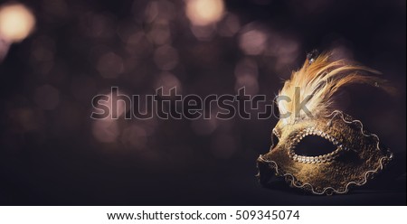 Golden venetian ball mask in front of the night bokeh lights. Masquerade party or holiday event celebration concept. 