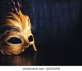 Golden venetian ball mask over dark background with copyspace. Masquerade party or holiday event celebration concept.