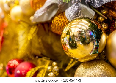 A Golden Vinyl Christmas Tree Decorated With Gold, And Red Ornaments And Balls, And Orange Garland. Displayed At A Local Shop Or Department Store For Sale.