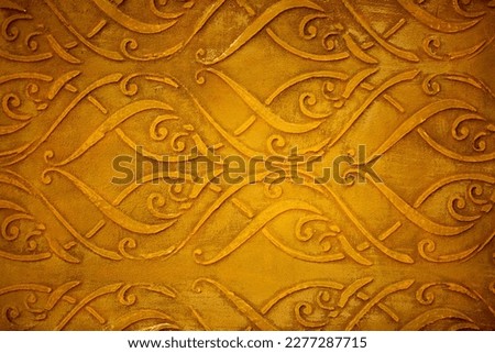 Golden wall with abstract spots as a background. Beautiful golden texture with patterns, decorative plaster. Modern bright wall painting in trendy shades, unusual spotted yellow and gold surface.