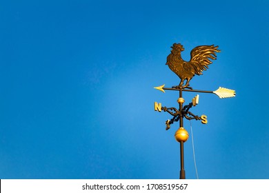 Golden weathercock shining in the blue sky