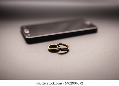 golden wedding rings on a mobile phone. Concept of infidelity or virtual betrayal through the smartphone.
