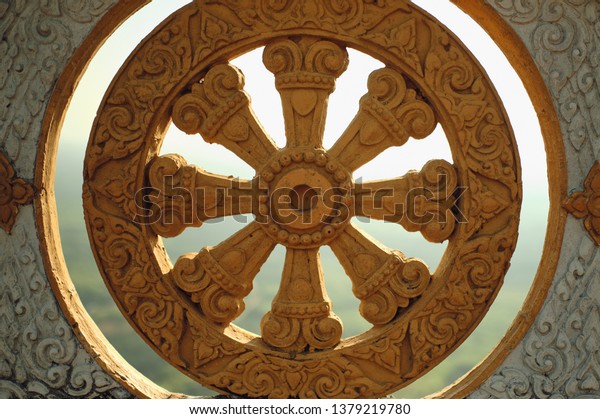 Golden\
wheel of Dharma on the wall of an Asian\
temple