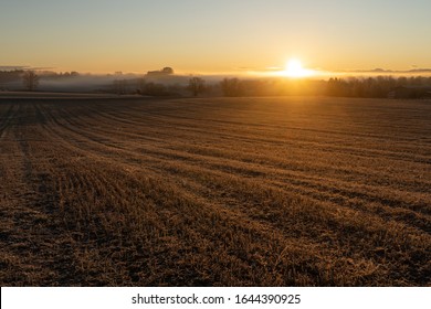 Golden Winter Sunrise Upon A Harvested Field With A Bit Of Mist In The Disrance