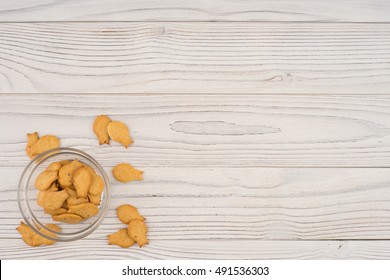 Goldfish Cracker In A Glass Bowl On A White Wooden Table. Top View.