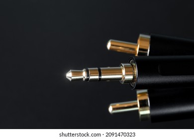 The gold-plated RCA connectors and TRS connector for sound transmission, audio cable for excellent sound quality on black background. Close-up. Shallow depth of field.