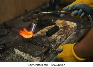 Goldsmith holding crucible with precious metal during smelting