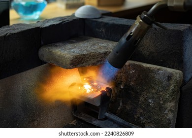 Goldsmith melting silver and gold with a blowtorch and pouring it in a mold to make wedding or engagement rings - Powered by Shutterstock