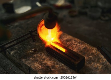 Goldsmith pouring melted metal into the mold - Shutterstock ID 2002612364