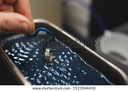 Goldsmith's hand cleaning a ring using an ultrasonic cleaner.