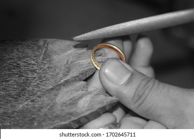 Goldsmith's hand making a gold silver jewelry with precious gemstone cutting rough stone using jewelry's tools with selective focus 