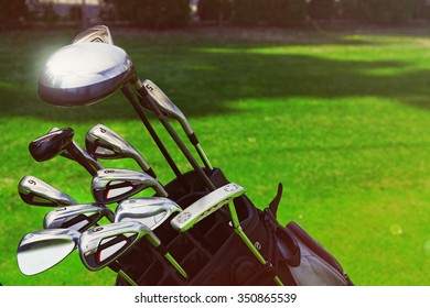 Golf Bag With Clubs On Green Field, Close Up