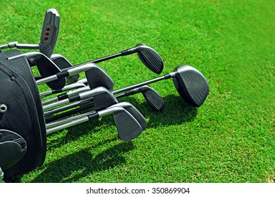 Golf bag with clubs on green field, close up