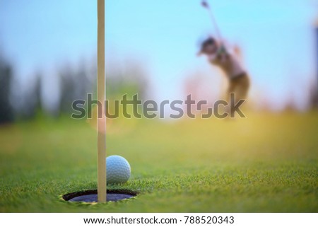 golf ball atmost on the edge of the hole on the green by golf player hit the ball from apron green to the hole