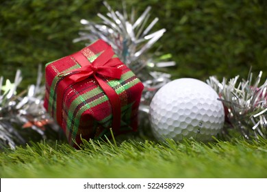 golf ball and Christmas gift box on green grass background