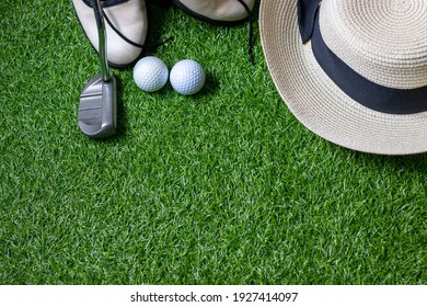 Golf ball with golf club and hat are on green grass