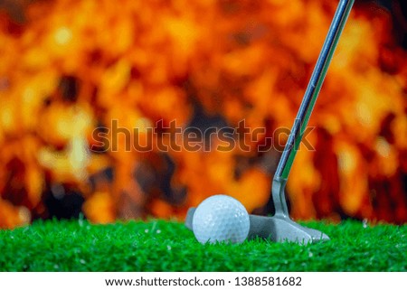 Golf ball and golf club on grass green for golfer putting it on fire flame background  