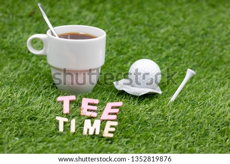 Golf ball with cup of tea are on green grass