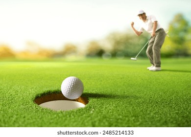 Golf ball drop into the hole after golfer putting. - Powered by Shutterstock