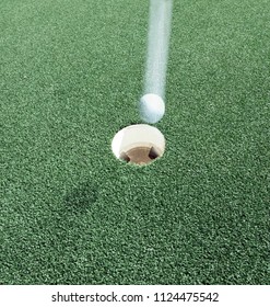 A Golf Ball Falling From Above Into The Hole.  A Hole In One.