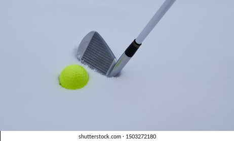 A golf ball and iron on the snow.