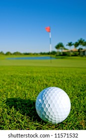golf ball near green and pin of lovely tropical golf course with clear blue sky