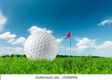 Golf Ball On Green Grass Close Up And The Flag
