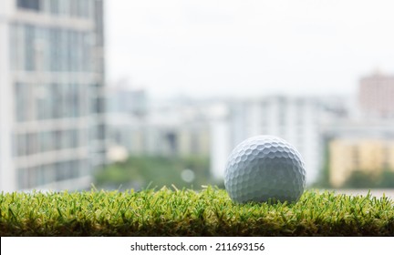 Golf Ball On Green Grass (artificial Turf) With Building Background