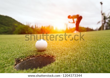 Golf ball on green grass ready to be struck at golf club,close up in golf coures at Thailand