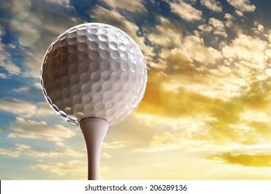 Golf ball on tee about to tee off against a sunset sky
