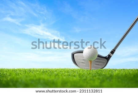 Golf ball on tee and driver golf club with blue sky background.
