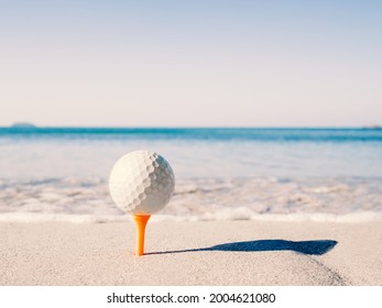 The golf ball is on the tee, embroidered on the sand beach with the sea in the background.