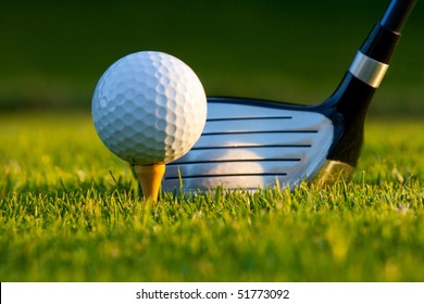 Golf Ball On Tee In Front Of Driver On A Gold Course