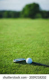 Golf Ball And Putter On The Green Grass Next To The Hole. Top View Of The Sporting Event For The Game Of Golf. Summer Vacation And Hobbies.