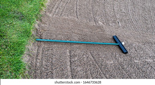 Golf Ball And Rake In  Sand Bunker