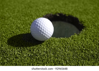 A golf ball sits at the lip of the hole on the putting green.