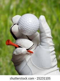 A Golf Ball And Tee Held In Hand With Glove.